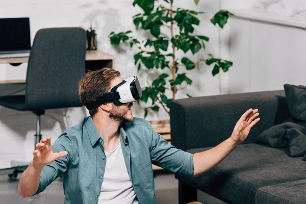 Enfoque selectivo de hombre joven usando auriculares de realidad virtual en casa - foto de stock