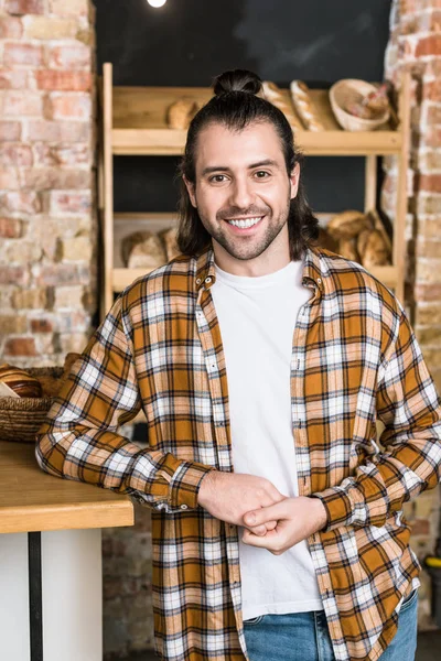 Smiling adult seller standing at workplace in bakery — Stock Photo