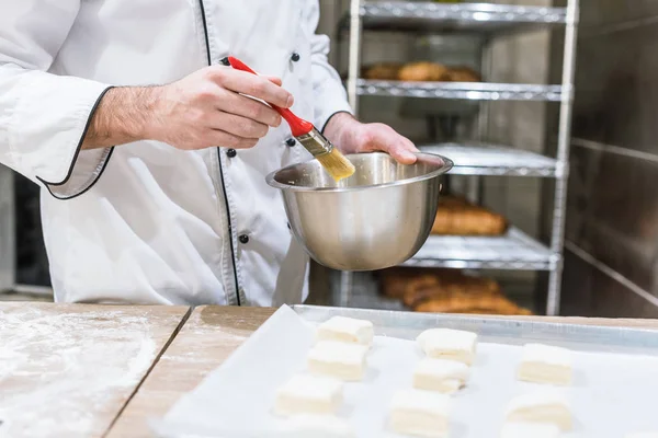 Nahaufnahme von Bäckerhänden, die Teigstücke mit Klebepinsel einölen — Stockfoto