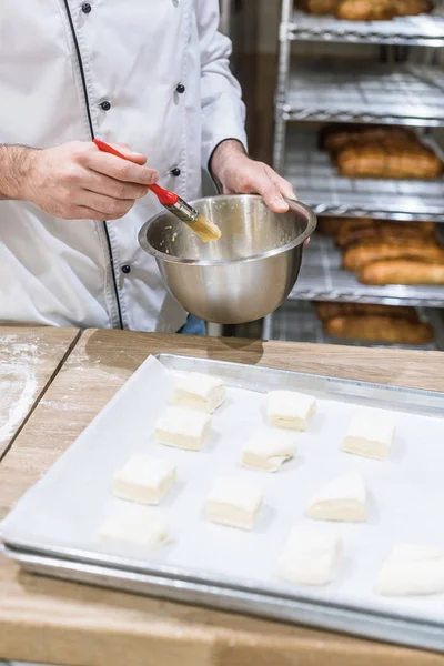 Fermer les mains des cuisiniers en huilant les morceaux de pâte avec une brosse à badigeonner — Stock Photo