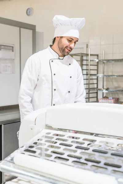 Padeiro bonito em uniforme de chef na cozinha da padaria — Fotografia de Stock