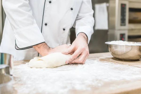 Primo piano delle mani del fornaio con pasta cruda sul tagliere — Foto stock