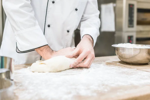 Close up of baker hands with uncooked dough on cutting board — Stock Photo