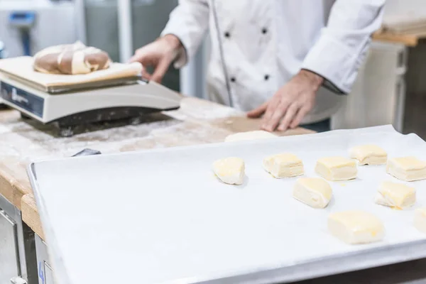 Обрезанный вид пекаря, взвешивающего тесто на кухонных весах — стоковое фото