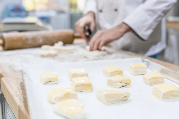 Primer plano de masa sin cocer en la cocina con el chef en el fondo - foto de stock