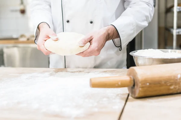 Panettiere che tiene la pasta cruda in mani — Foto stock