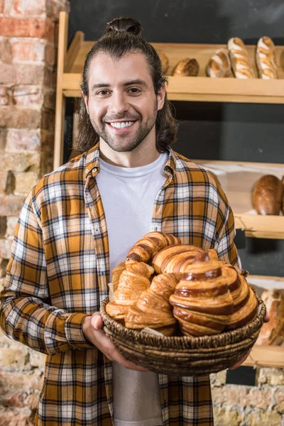 Handsome seller holding pastry in wicker basket — Stock Photo