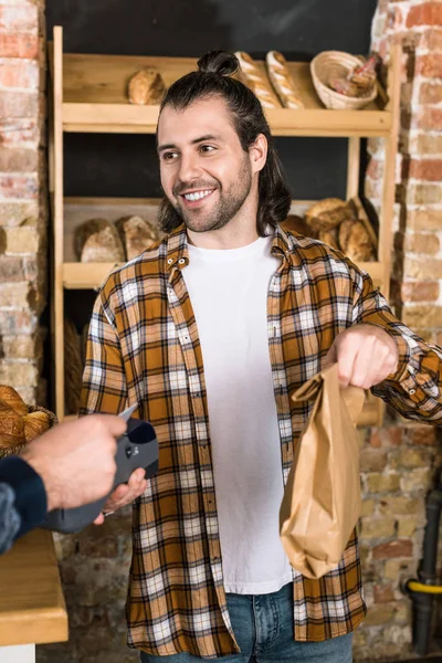 Клієнт, який платить кредитною карткою та продавцем чоловіків, тримає паперовий пакет — стокове фото