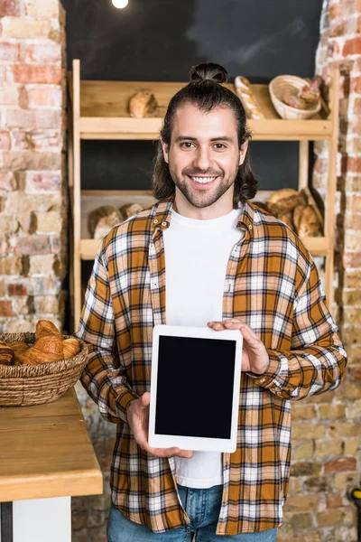 Vendedor guapo sosteniendo tableta digital en panadería - foto de stock