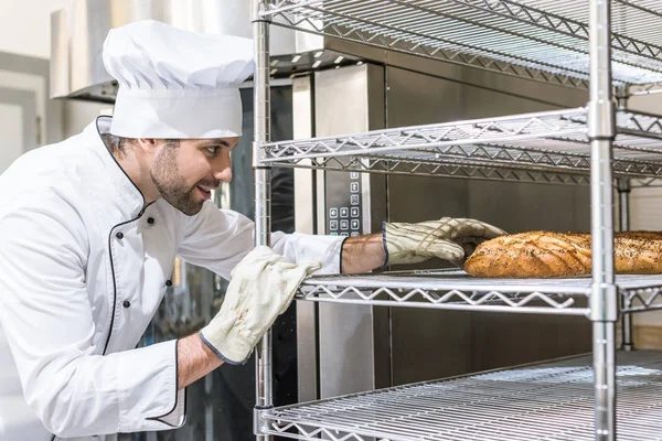 Вид збоку пекарні в рукавичках, що приймають хліб — стокове фото