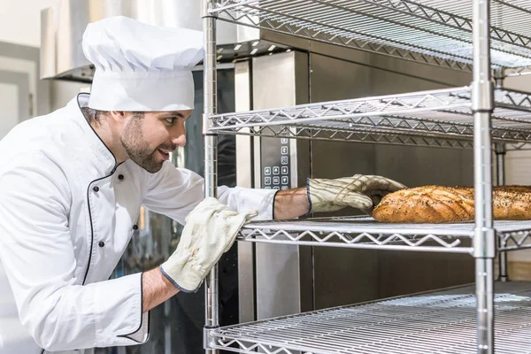 Vista laterale del panettiere in guanti che prende il pane — Foto stock