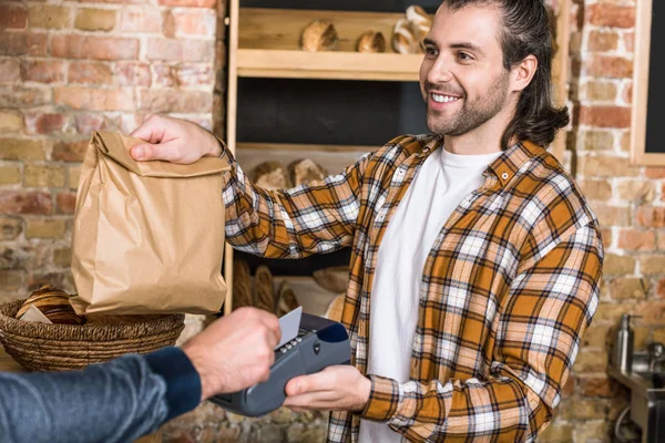 Cliente pagando com cartão de crédito e vendedor segurando saco de papel — Fotografia de Stock