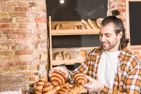 Handsome seller holding pastry in bakehouse — Stock Photo