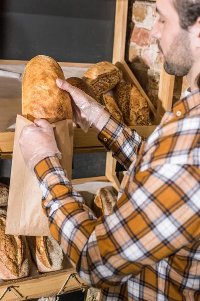 Uomo mettere il pane appena sfornato nel sacchetto di carta — Foto stock