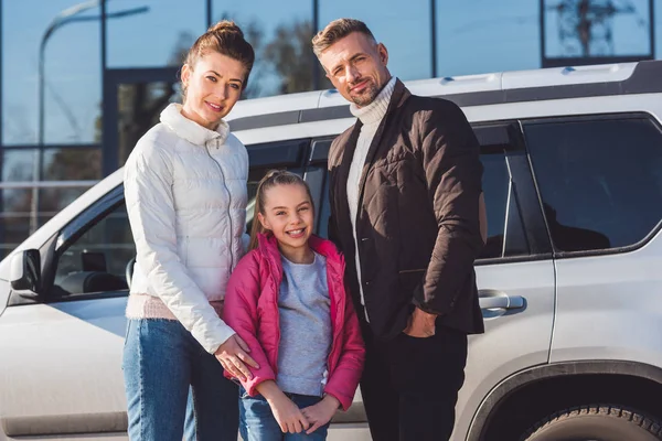 Preteen daughter standing with mom and dad near car — Stock Photo