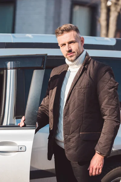 Hombre guapo de pie cerca del coche con la puerta abierta - foto de stock