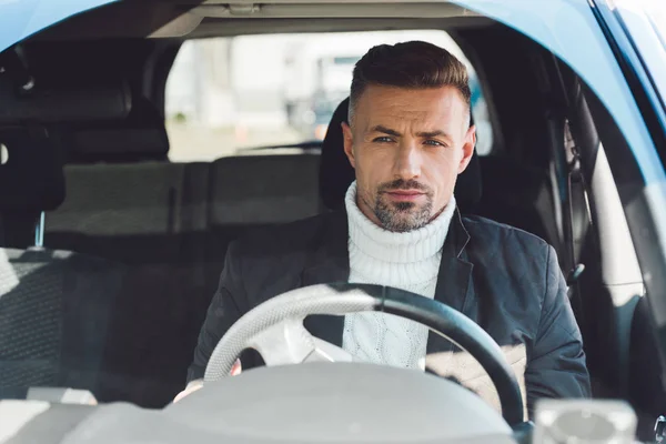 Красивый мужчина в свитере и куртке сидит в машине — стоковое фото