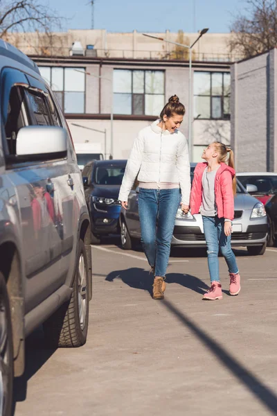 Madre e figlia che camminano e si tengono per mano vicino auto — Foto stock