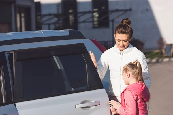 Mom opening car door and standing with daughter — Stock Photo