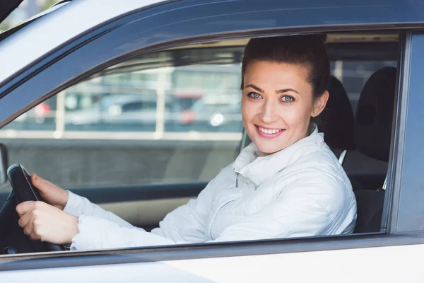 Beautiful woman sitting in car and holding steering wheel — Stock Photo
