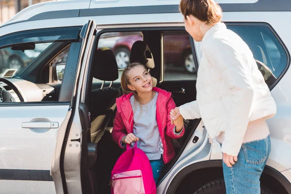 Mamma aiuta la figlia ad uscire dalla macchina — Foto stock