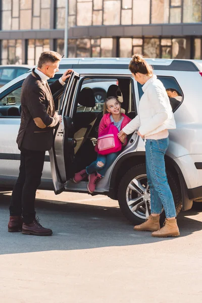 П'ятнадцять донька сидить у машині з відкритими дверима і тримає руку мами — стокове фото