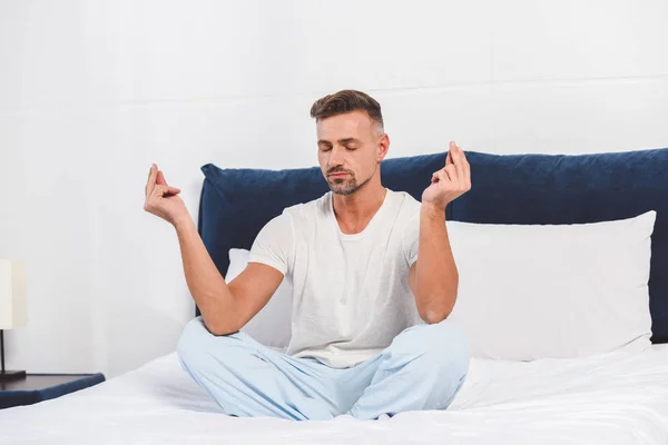 Bello uomo che pratica yoga in camera da letto — Foto stock