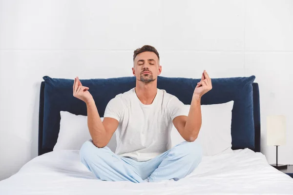 Schöner Mann praktiziert Yoga im Pyjama — Stockfoto
