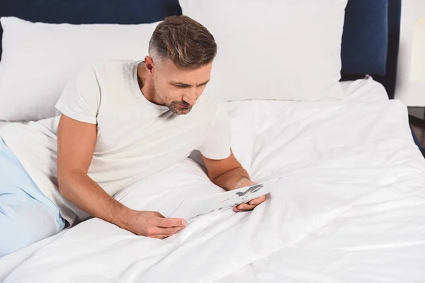 Hombre guapo leyendo periódico en el dormitorio - foto de stock