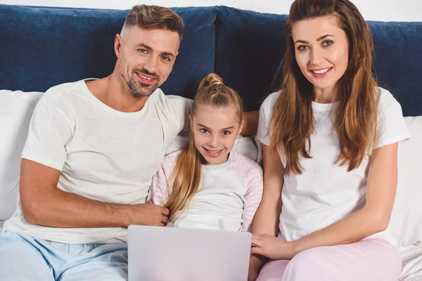 Веселая семья лежит в ночной одежде с ноутбуком — стоковое фото