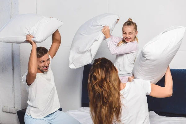 Alegre familia tener almohada lucha en el dormitorio - foto de stock