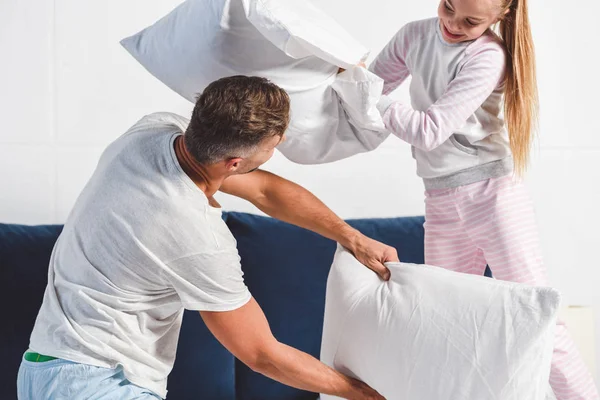 Papá e hija teniendo pelea de almohadas en casa - foto de stock