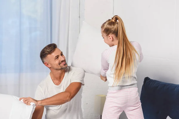 Padre e hija teniendo pelea de almohadas en el dormitorio - foto de stock