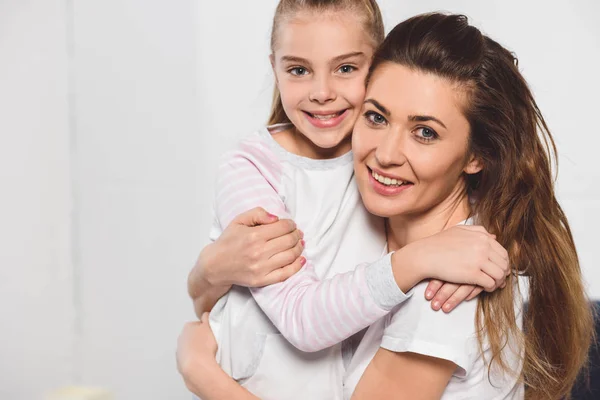 Mutter und Tochter umarmen und lächeln im Schlafzimmer — Stockfoto