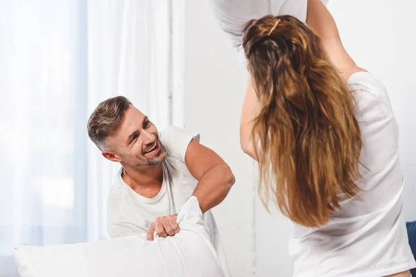 Alegre marido teniendo almohada lucha con esposa en casa - foto de stock