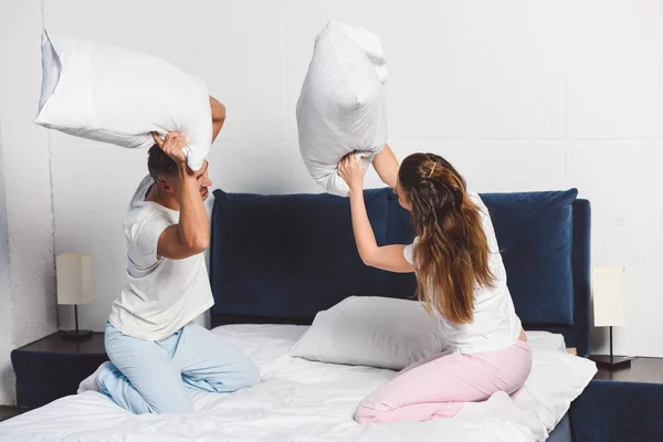 Couple joyeux ayant bataille d'oreillers dans la chambre — Photo de stock