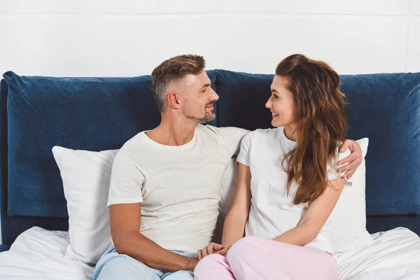 Pareja mirándose y sonriendo en pijama - foto de stock