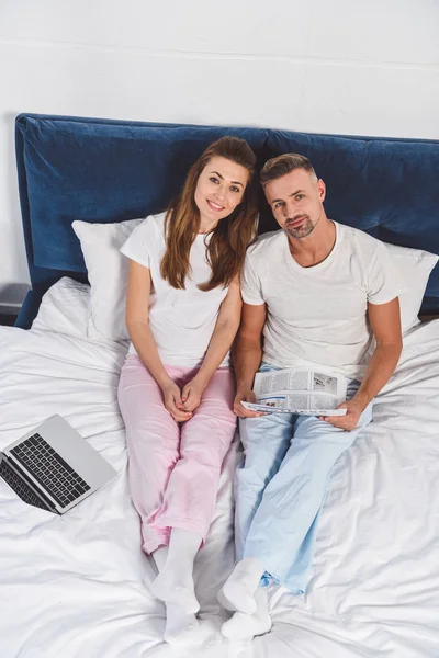 Vista aérea del marido y la esposa con portátil y periódico - foto de stock