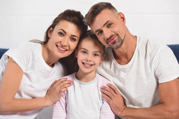 Happy smiling parents hugging daughter in pajamas — Stock Photo