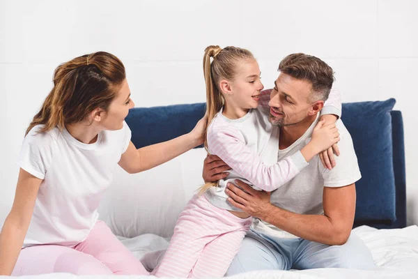 Happy family in pajamas hugging in bed — Stock Photo