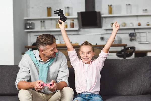 Feliz filha regozijando vitória enquanto joga videogame com o pai — Fotografia de Stock