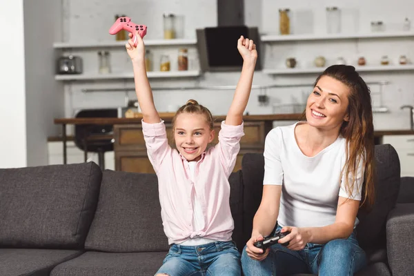 Feliz hija regocijo victoria mientras juega videojuego con la madre - foto de stock