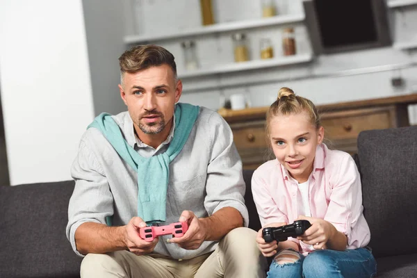 Concentrée souriante fille jouer jeu vidéo avec père — Photo de stock