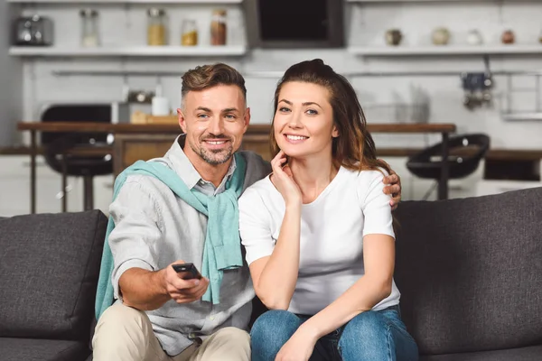 Marido e mulher sentados no sofá e assistindo tv juntos — Fotografia de Stock