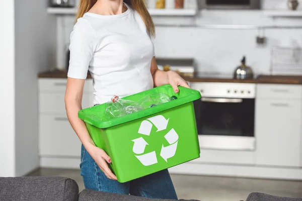 Обрезанный вид женщины, держащей зеленую коробку с табличкой утилизации и пустыми пластиковыми бутылками — стоковое фото