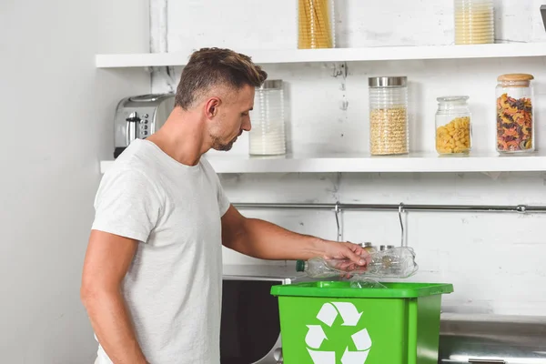 Schöner Mann legt leere Plastikflasche in grüne Recyclingbox — Stockfoto