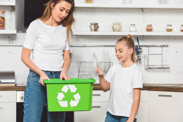 Mère et fille mettre des bouteilles en plastique vides à la boîte de recyclage verte ensemble — Photo de stock