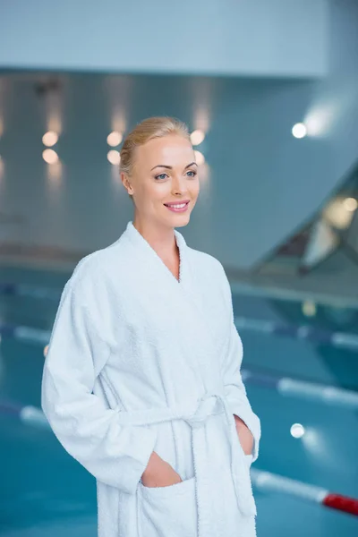 Beautiful woman standing in bathrobe with hands in pockets — Stock Photo