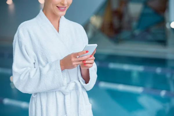 Ausgeschnittene Ansicht einer Frau mit Smartphone in Poolnähe — Stockfoto