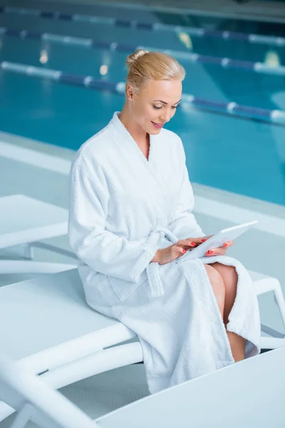 Belle femme assise sur une chaise longue avec tablette numérique — Photo de stock